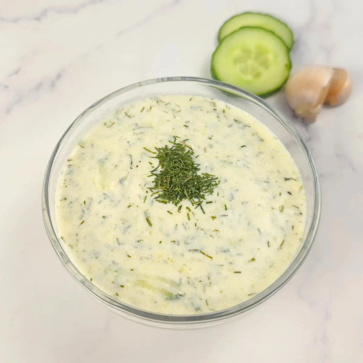 Creamy keto tzatziki sauce in a glass bowl topped with fresh dill