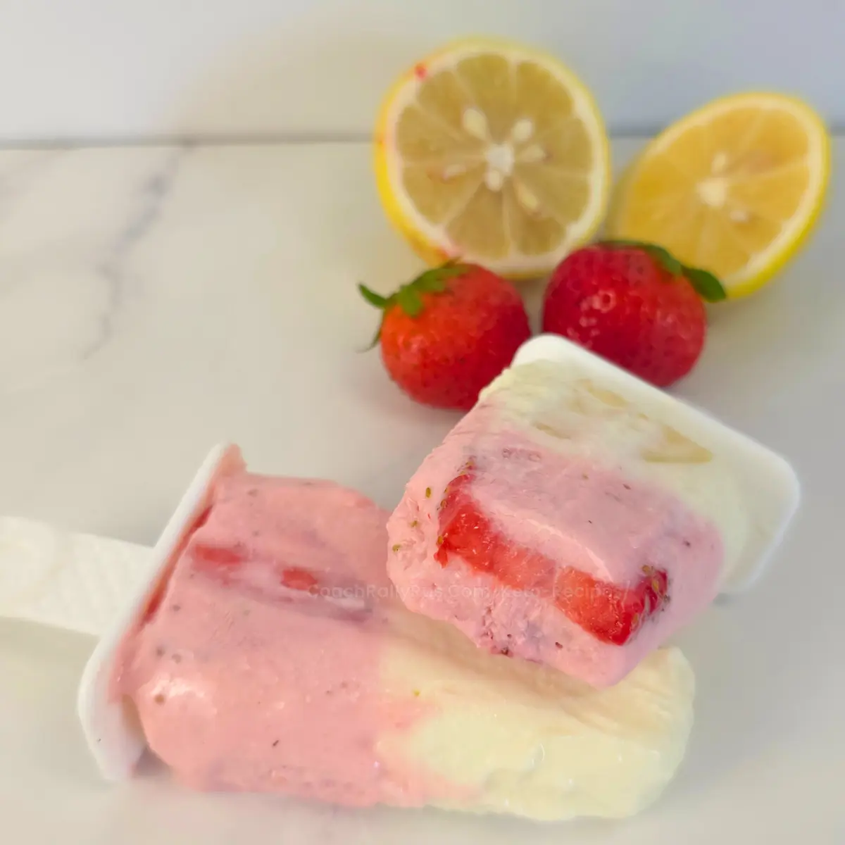 Keto strawberry lemonade popsicle with visible fruit pieces on white background