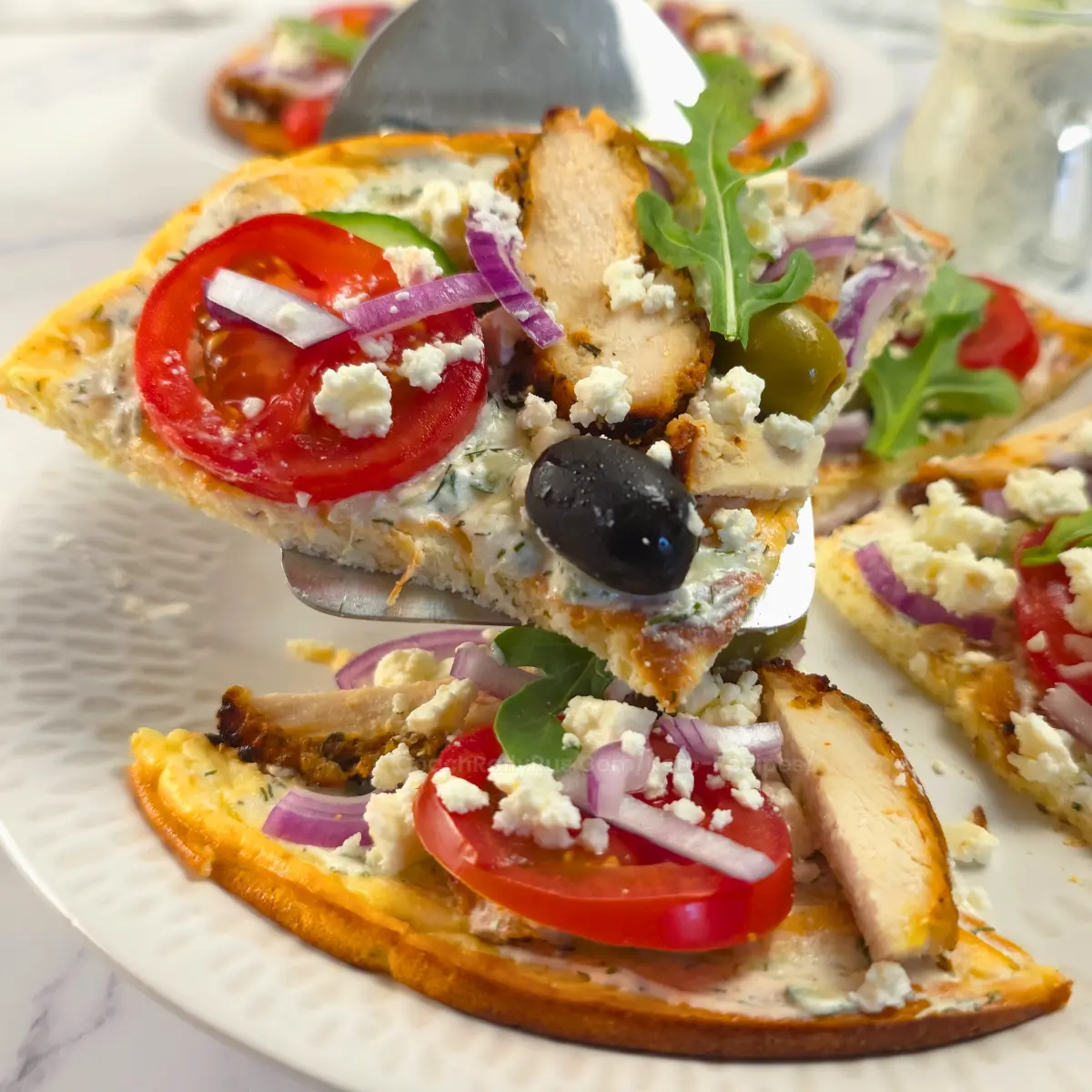 Chicken gyros flatbread pizza slice with feta, tomato, and olives
