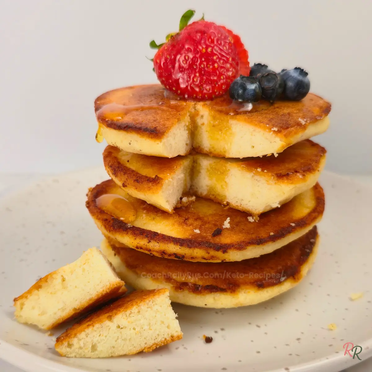 Stack of fluffy almond flour pancakes with syrup and berries